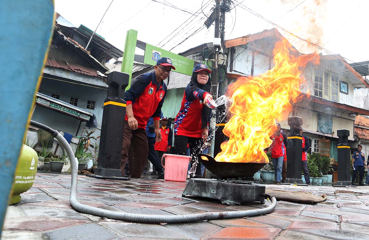 Petugas mengarahkan seorang warga yang menggunakan alat pemadam api ringan (APAR) saat simulasi penanggulangan kebakaran di Perkampungan Menteng Tenggulun, Jakarta, Kamis (9/10/2025)  (Beritanasional.com/Oke Atmaja)
