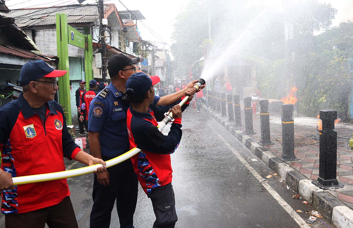 Petugas mengarahkan seorang warga yang menggunakan alat pemadam api ringan (APAR) saat simulasi penanggulangan kebakaran di Perkampungan Menteng Tenggulun, Jakarta, Kamis (9/10/2025)  (Beritanasional.com/Oke Atmaja)