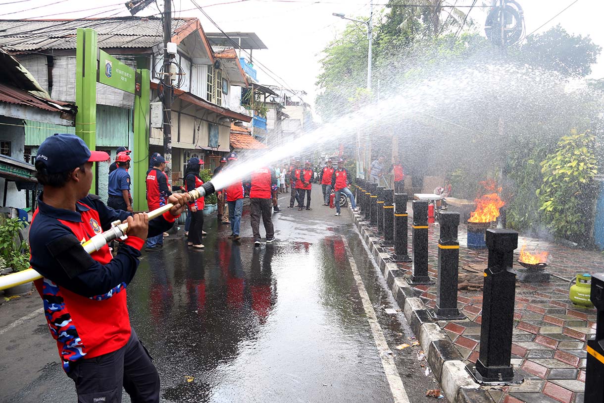 Petugas mengarahkan seorang warga yang menggunakan alat pemadam api ringan (APAR) saat simulasi penanggulangan kebakaran di Perkampungan Menteng Tenggulun, Jakarta, Kamis (9/10/2025)  (Beritanasional.com/Oke Atmaja)