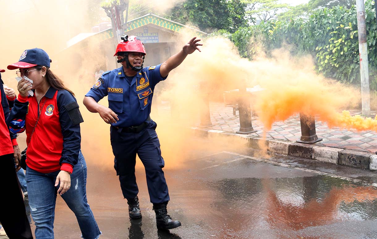 Petugas mengarahkan seorang warga yang menggunakan alat pemadam api ringan (APAR) saat simulasi penanggulangan kebakaran di Perkampungan Menteng Tenggulun, Jakarta, Kamis (9/10/2025)  (Beritanasional.com/Oke Atmaja)
