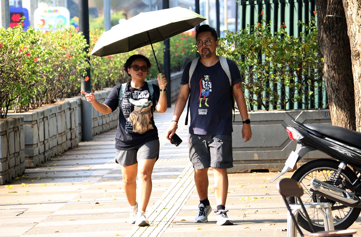 Warga mengenakan penutup kepala saat cuaca terik di kawasan Bundaran HI, Jakarta, Rabu (15/10/2025). (Beritanasional.com/Oke Atmaja)
