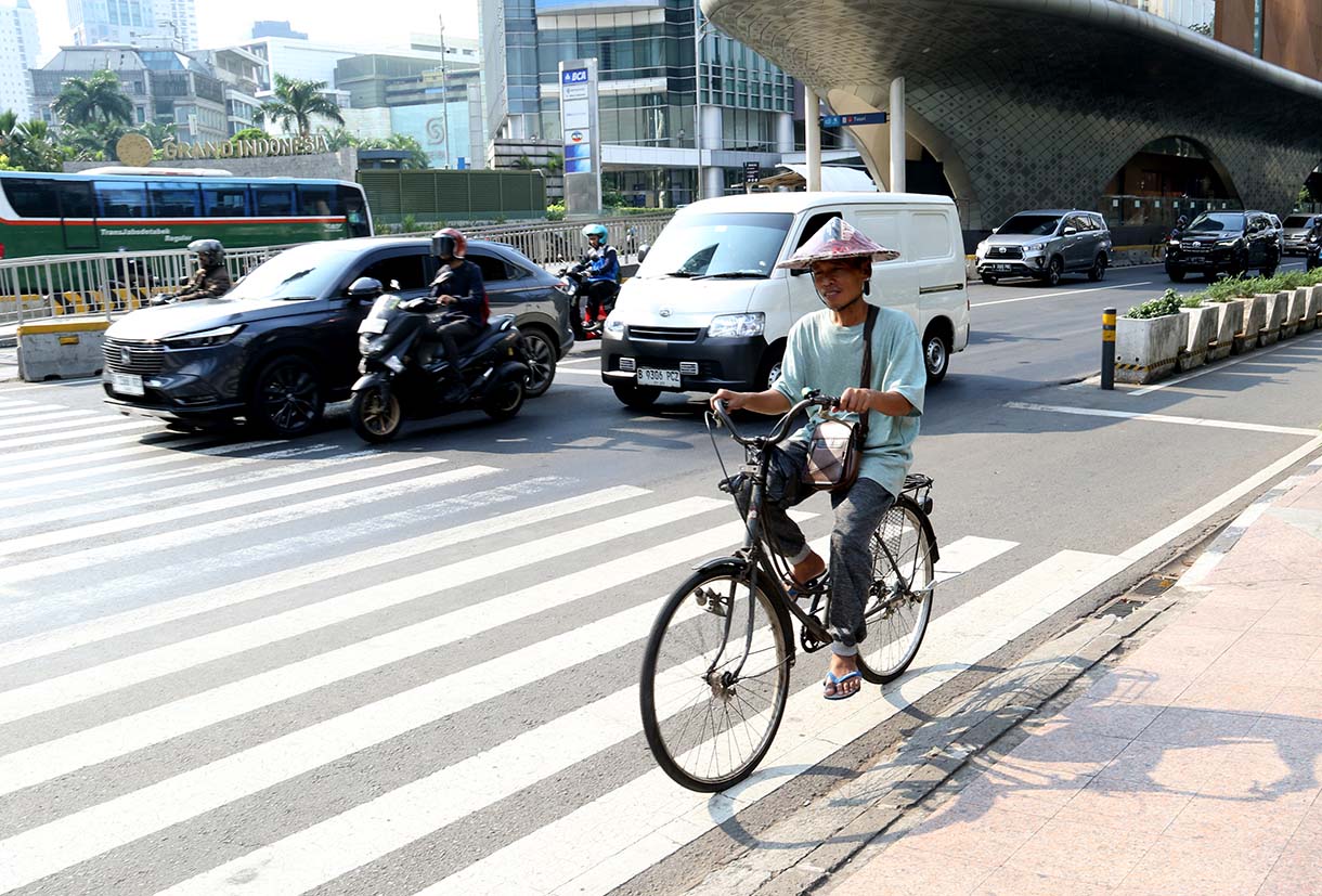 Warga mengenakan penutup kepala saat cuaca terik di kawasan Bundaran HI, Jakarta, Rabu (15/10/2025). (Beritanasional.com/Oke Atmaja)