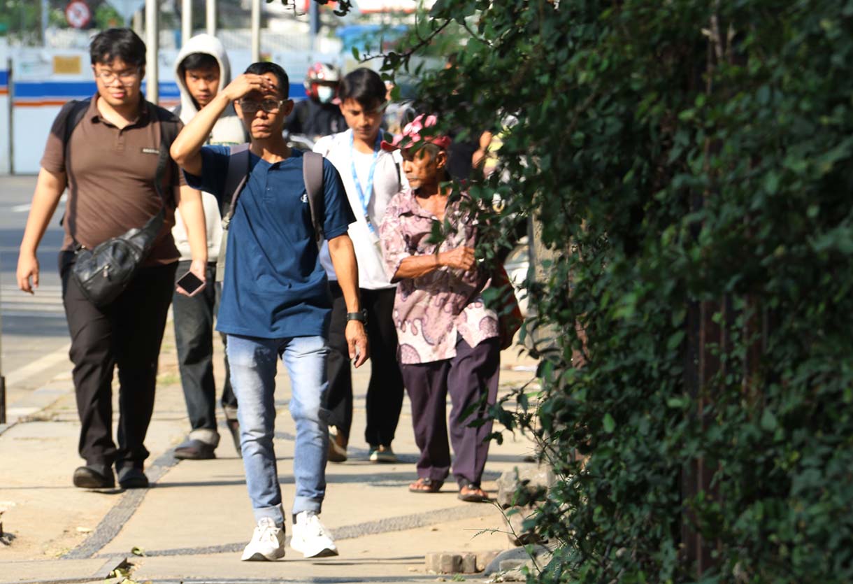 Warga mengenakan penutup kepala saat cuaca terik di kawasan Bundaran HI, Jakarta, Rabu (15/10/2025). (Beritanasional.com/Oke Atmaja)