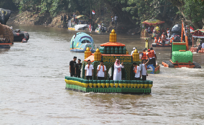 Peserta beratraksi di atas perahu unik berbahan limbah plastik saat parade Festival Cinta Lingkungan di Kali Ciliwung, Cikoko, Jakarta Selatan, Minggu (28/9/2025). (Berita nasional.com/Oke Atmaja)