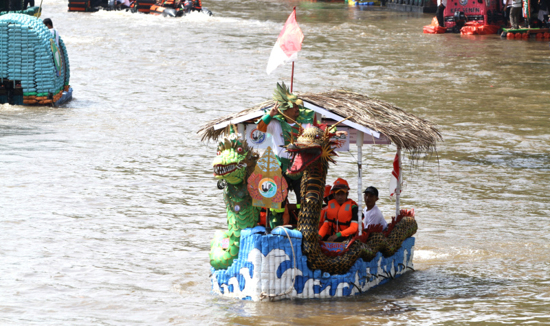Peserta beratraksi di atas perahu unik berbahan limbah plastik saat parade Festival Cinta Lingkungan di Kali Ciliwung, Cikoko, Jakarta Selatan, Minggu (28/9/2025). (Berita nasional.com/Oke Atmaja)