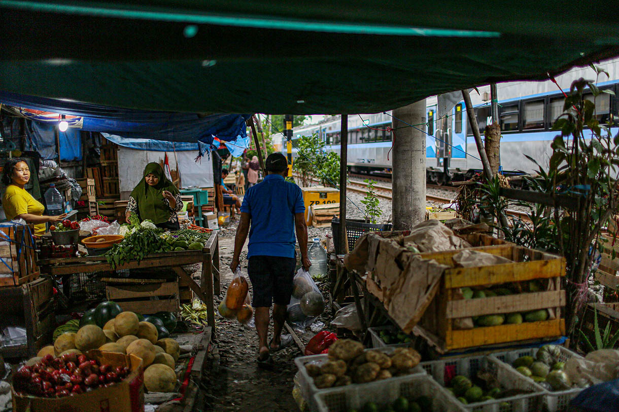 Pedagang menata dagangannya saat kereta api melintas yang berada Pasar Gaplok, lIntasan rel Kramat Sentiong-Pasar Senen kawasan Tanah Tinggi, Jakarta Pusat, Senin (11/11/2024).(BeritaNasional.com/Oke Atmaja)