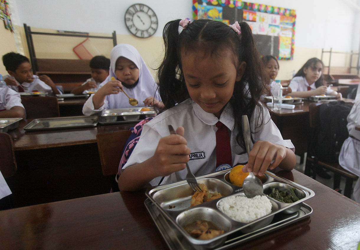 Murid menyantap makanan bergizi gratis di SD Barunawati  Slipi, Jakarta, Senin (6/1/2025).(BeritaNasional.com/Oke Atmaja)