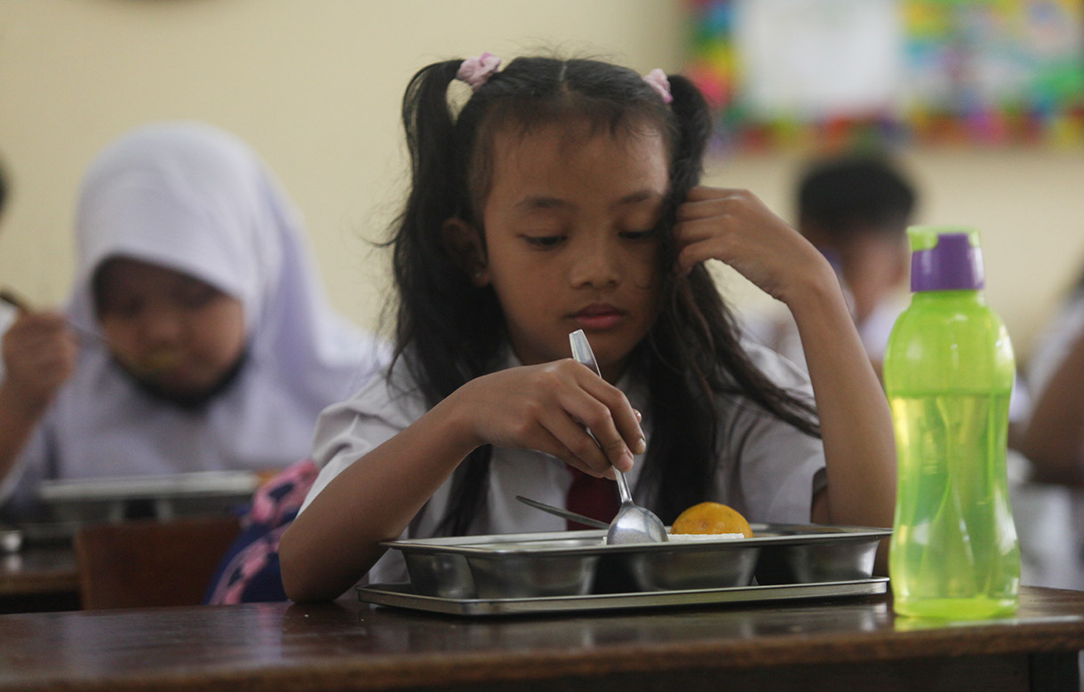 Murid menyantap makanan bergizi gratis di SD Barunawati  Slipi, Jakarta, Senin (6/1/2025).(BeritaNasional.com/Oke Atmaja)