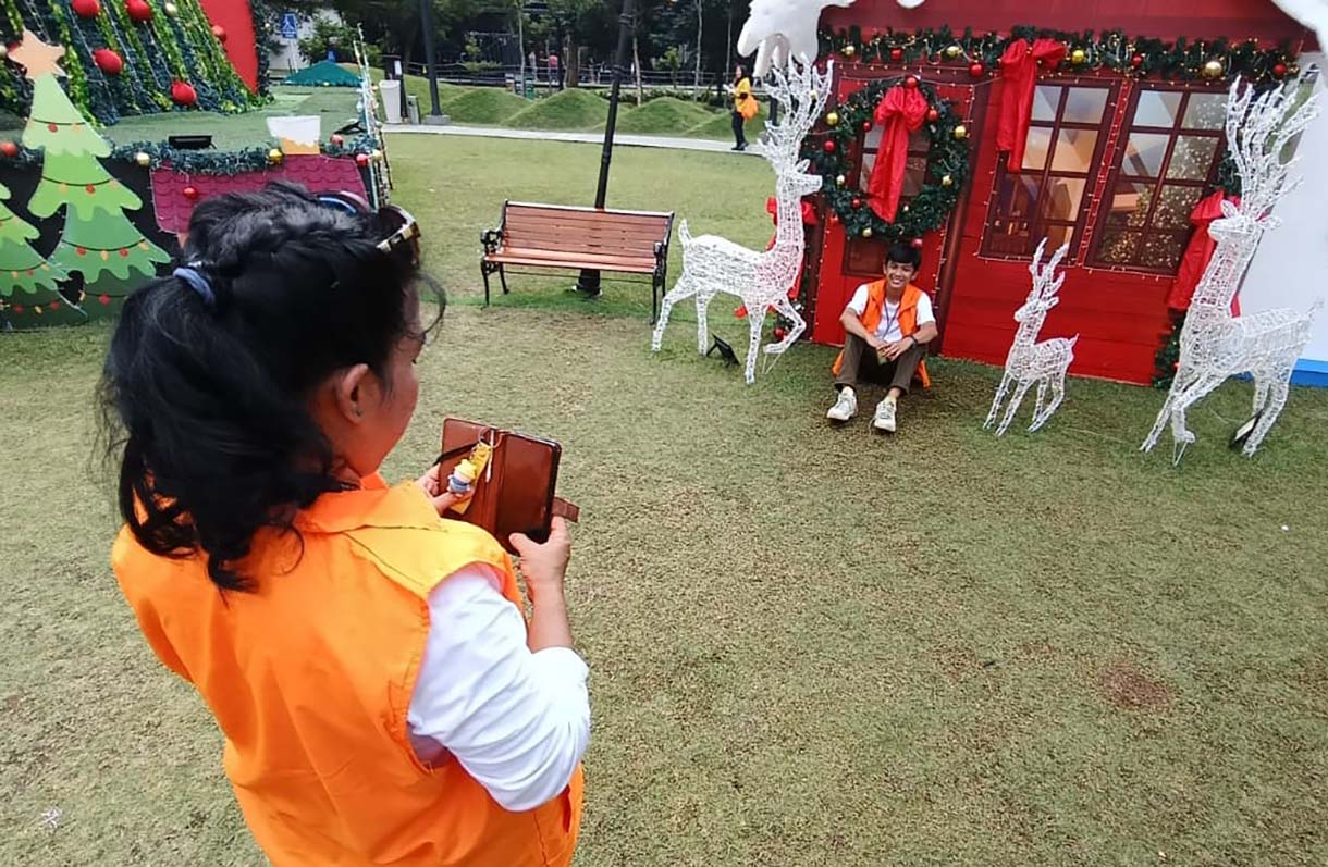 Warga berfoto di dekat dekorasi pohon Natal di West lobby, One Satrio, Jakarta, Sabtu (6/12/2025).  (Beritanasional.com/Oke Atmaja)