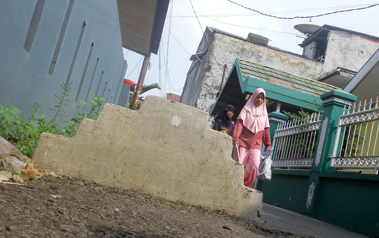 Warga melintas disamping kuburan di gang RT 03 RW 04 Kelurahan Pisangan Timur,Jakarta, Sabtu (13/7/2024) .(BeritaNasional.com/Oke Atmaja)