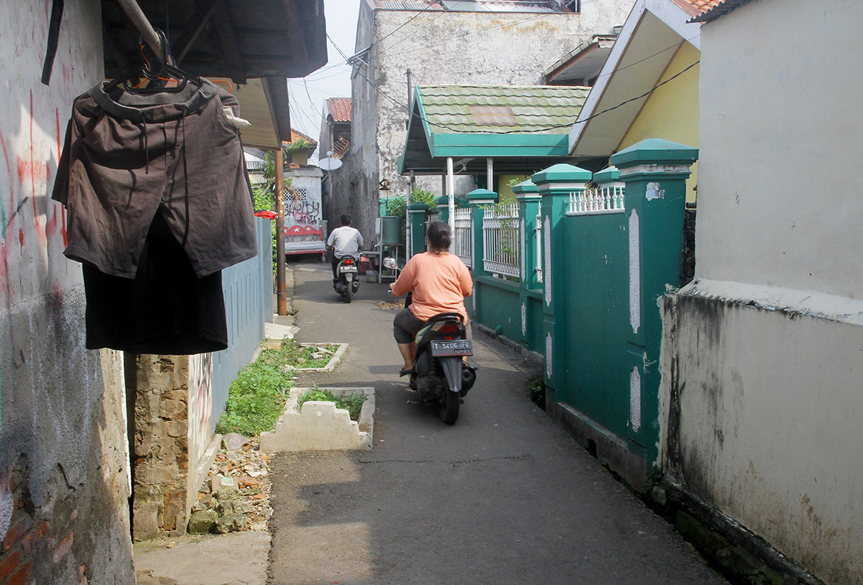 Warga melintas disamping kuburan di gang RT 03 RW 04 Kelurahan Pisangan Timur,Jakarta, Sabtu (13/7/2024) .(BeritaNasional.com/Oke Atmaja)