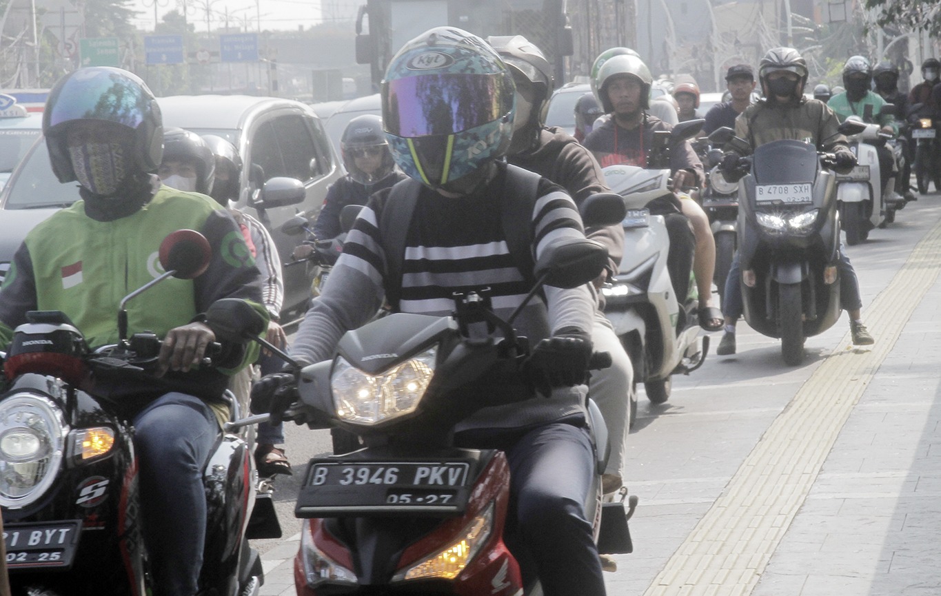 Warga berjalan di dekat pengendara motor yang melintasi trotoar di Jalan Matraman Raya, Jakarta, Selasa (26/4/2024).(Indonesiaglobe/Oke Atmaja)