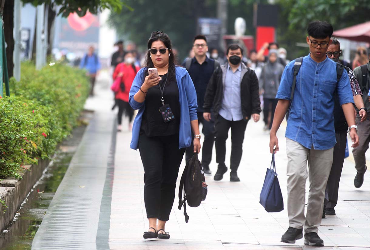 Pekerja melintas di jalan Jenderal Sudirman, Jakarta, Kamis (15/5/2025).  (Beritanasional.com/oke Atmaja)