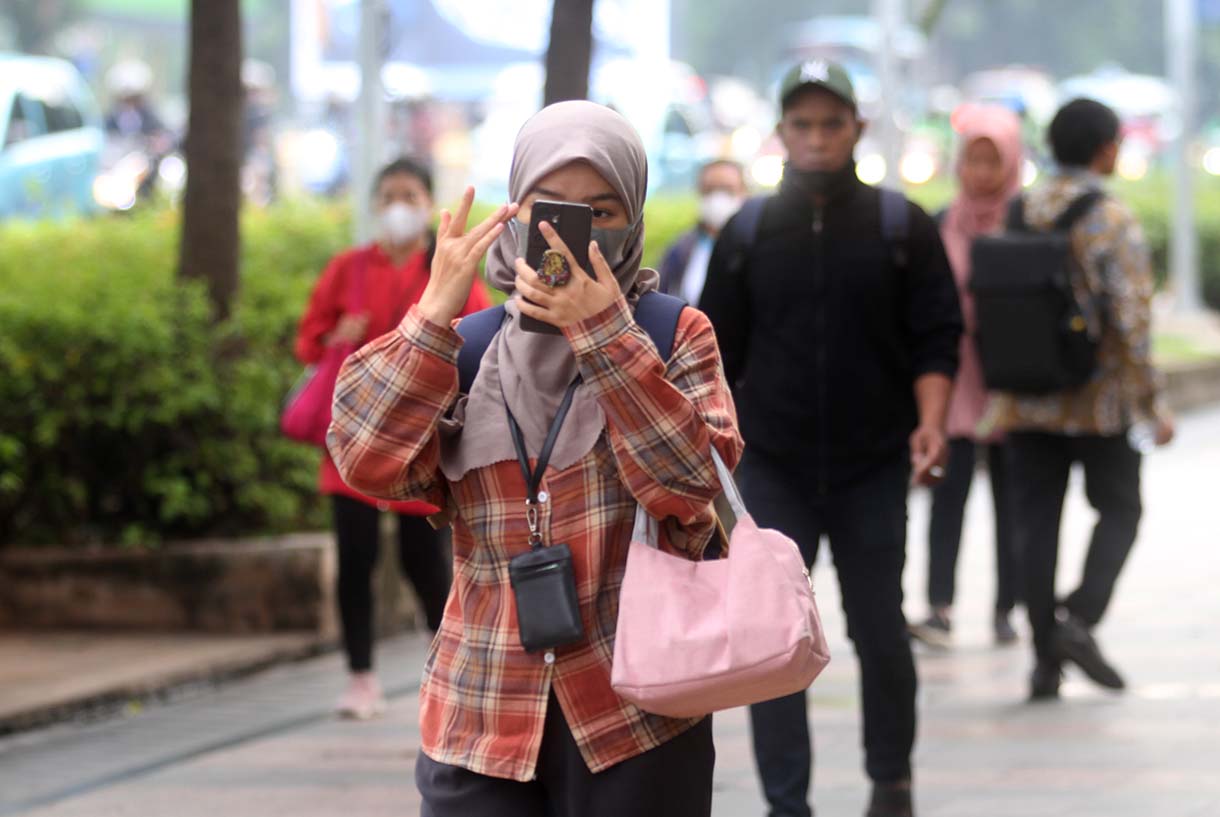 Pekerja melintas di jalan Jenderal Sudirman, Jakarta, Kamis (15/5/2025).  (Beritanasional.com/oke Atmaja)