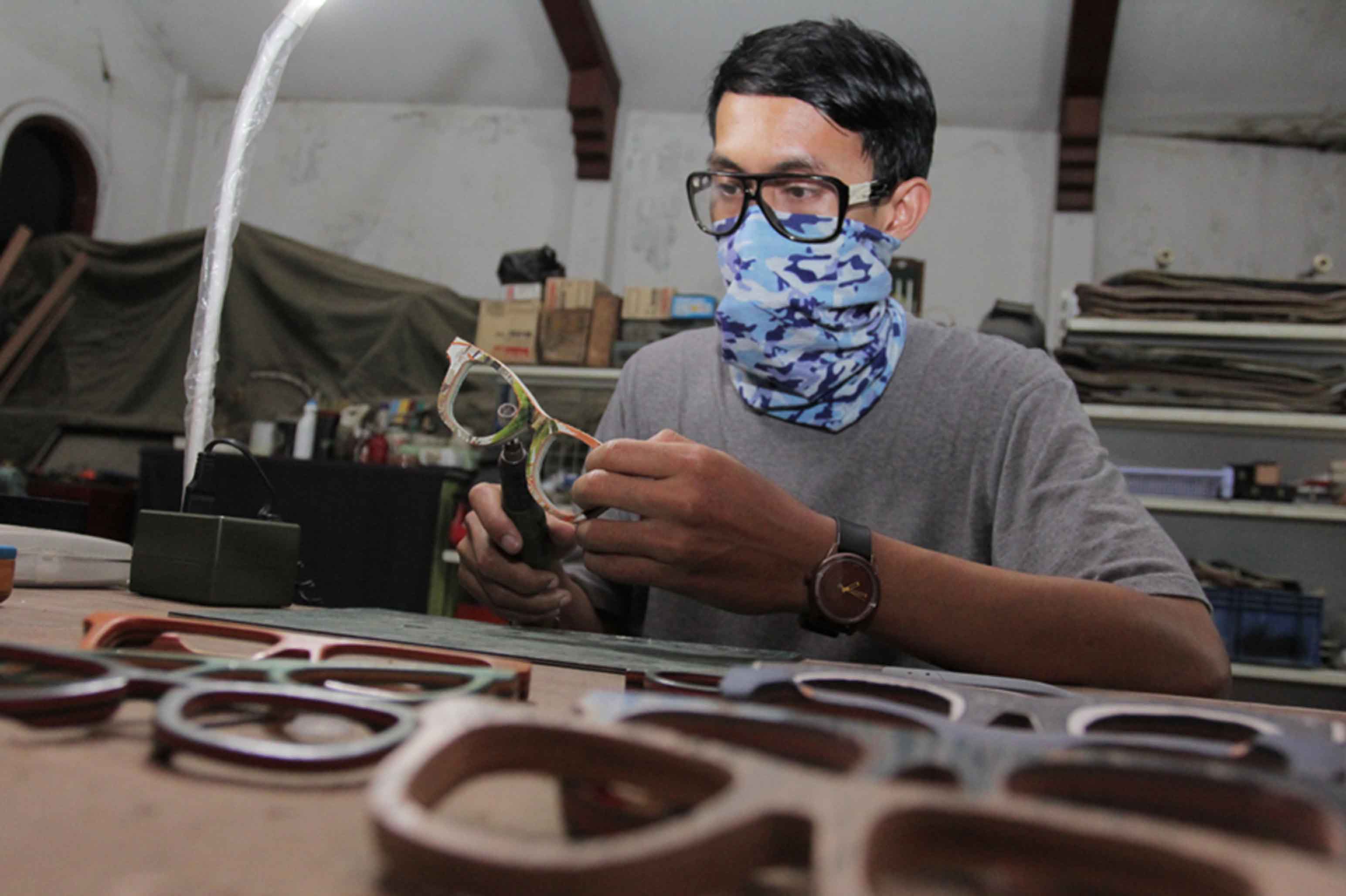 Perajin menyelesaikan pembuatan kacamata dari bahan kayu di kawasan Kramat Jati, Jakarta, Minggu (5/5/2024).(BeritaNasional.Com/Oke Atmaja)