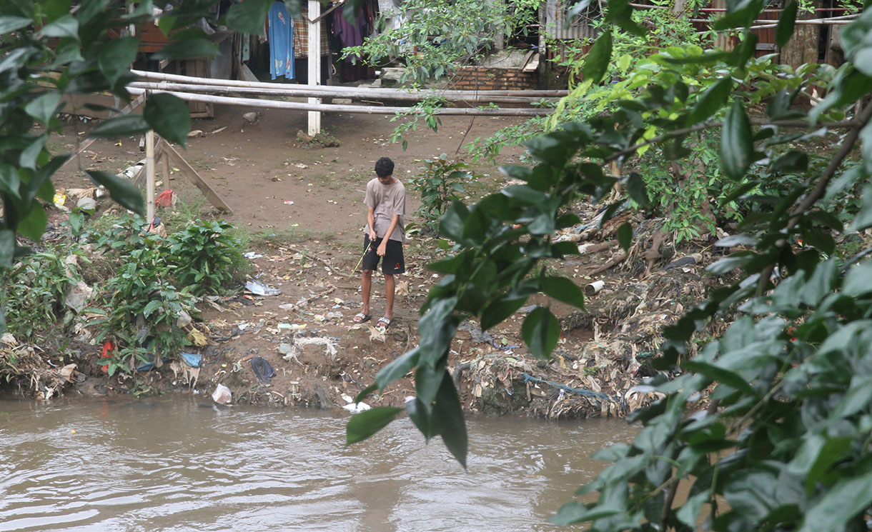 Warga memancing di aliran sungai Ciliwung kawasan Manggarai, Jakarta, Selasa (4/2/2025).(Beritanasional.com/Oke Atmaja)