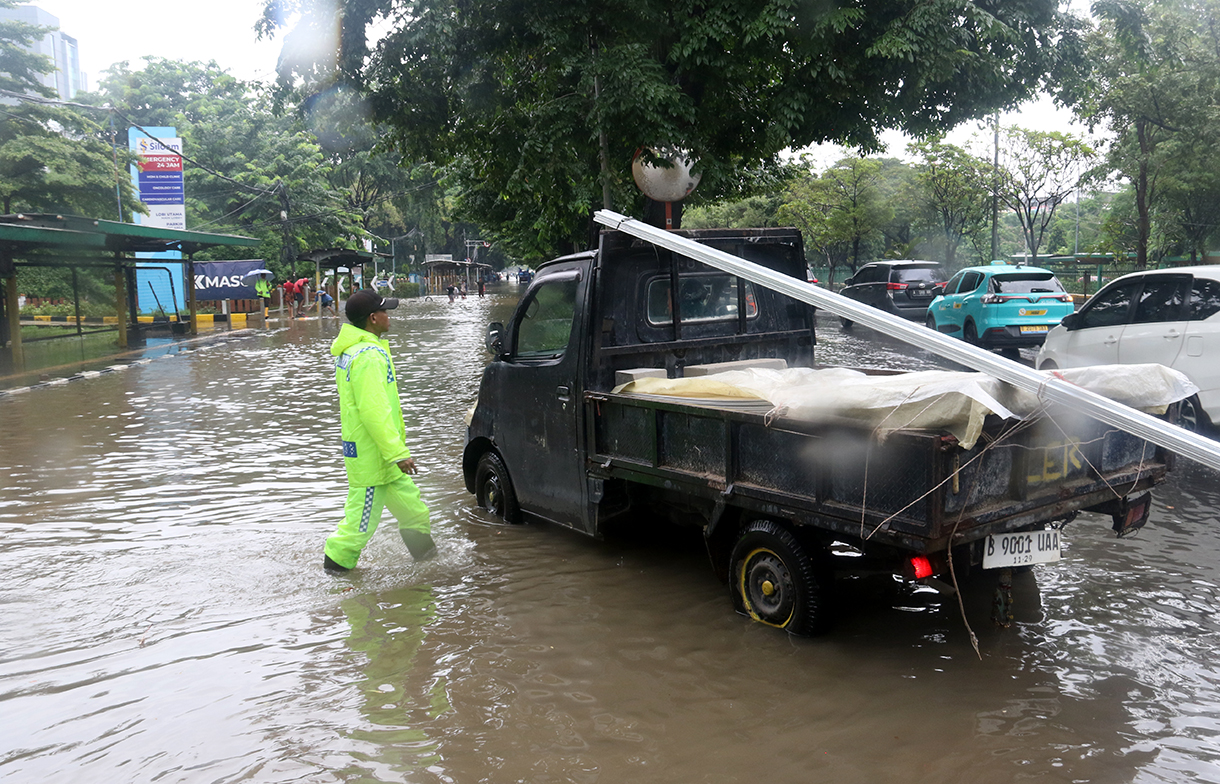 Petugas mengatur lalu lintas jalan di tengah genangan banjir yang merendam di sekitar Cempaka Putih, Jakarta, Kamis (22/1/2026).(Beritanasional.com/Oke Atmaja)