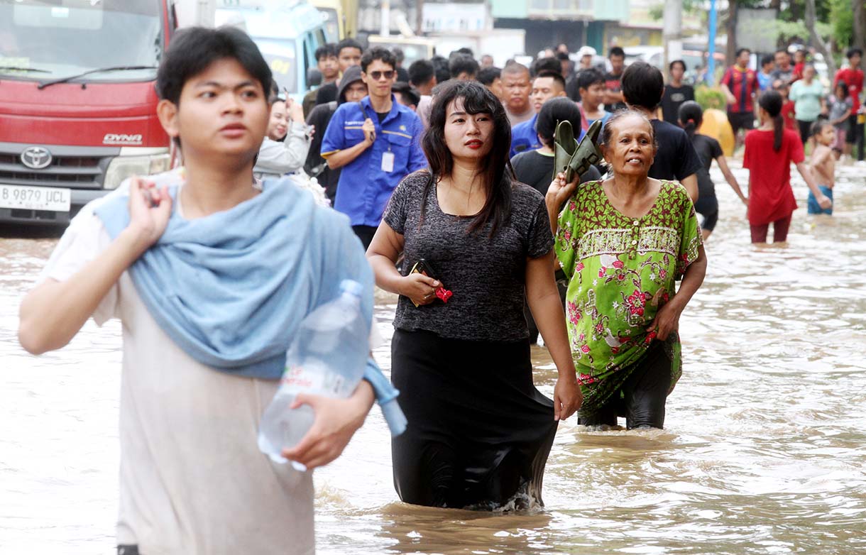 Warga melintasi banjir yang merendam rumah makan di jalan Jatinegara Barat, Jakarta, Selasa (4/3/2025).  (Beritanasional.com/Oke Atmaja)