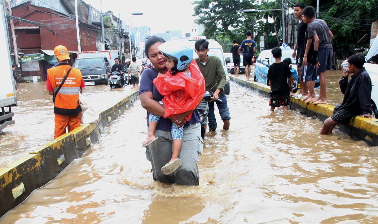 Warga melintasi banjir yang merendam rumah makan di jalan Jatinegara Barat, Jakarta, Selasa (4/3/2025).  (Beritanasional.com/Oke Atmaja)