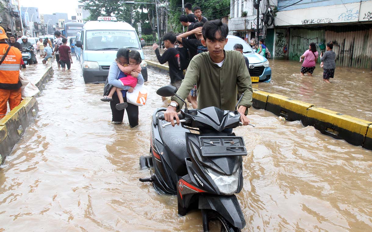 Warga melintasi banjir yang merendam rumah makan di jalan Jatinegara Barat, Jakarta, Selasa (4/3/2025).  (Beritanasional.com/Oke Atmaja)