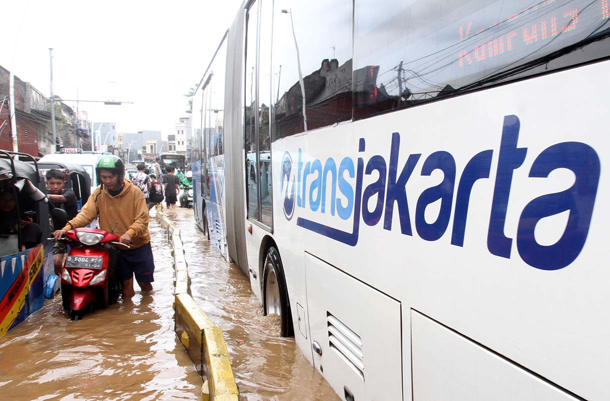 Warga melintasi banjir yang merendam rumah makan di jalan Jatinegara Barat, Jakarta, Selasa (4/3/2025).  (Beritanasional.com/Oke Atmaja)