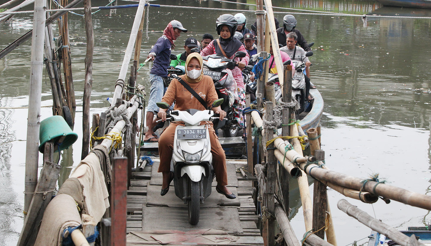 Sejumlah pengendara sepeda motor menggunakan perahu eretan menyeberangi Sungai Kali Angke di Kecamatan Penjaringan, Jakarta, Kamis (30/5/2024). (BeritaNasional.Com/Oke Atmaja)