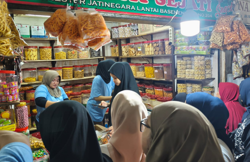 Pedagang melayani pembeli kue kering yang dijual di Pasar Jatinegara, Jakarta Timur, Selasa (17/3/2026). (Beritanasional.com/Oke Atmaja)