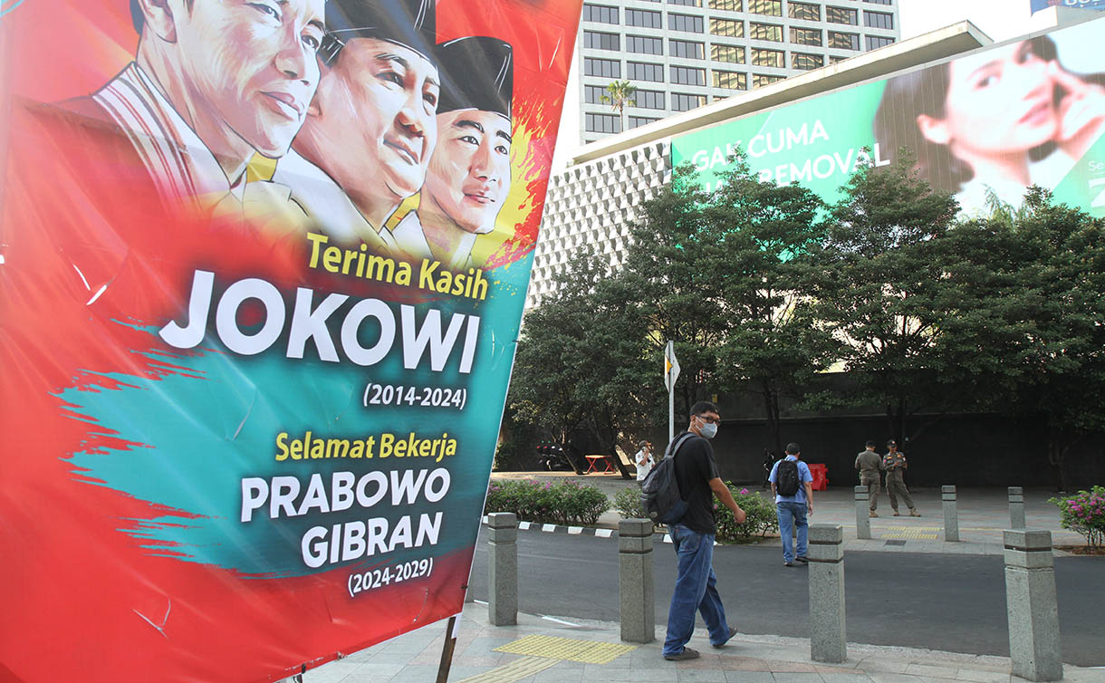 Warga berjalan di samping Baliho 'Terima Kasih Jokowi dan Selamat Bekerja Prabowo' di Jalan Jenderal Sudirman, Jakarta, Jumat (18/10/2024). (BeritaNasional.com/Oke Atmaja)