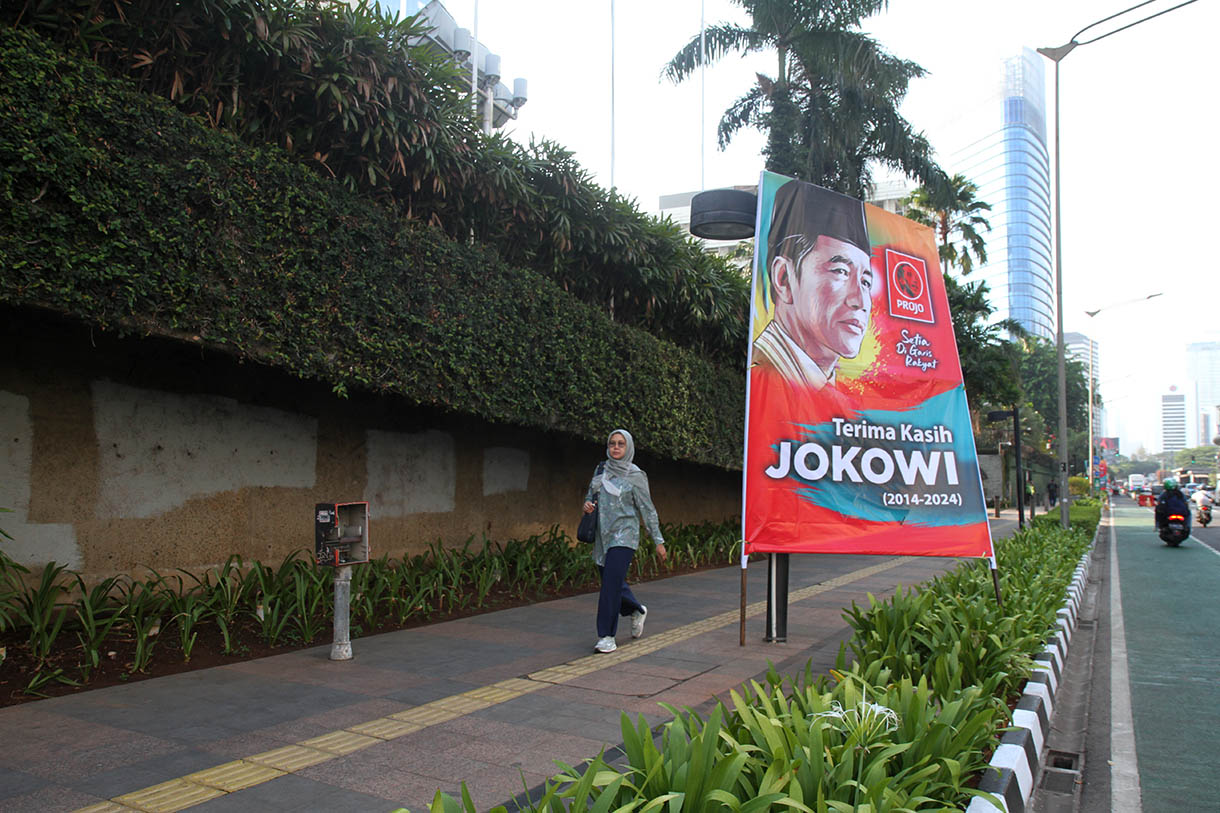 Warga berjalan di samping Baliho 'Terima Kasih Jokowi dan Selamat Bekerja Prabowo' di Jalan Jenderal Sudirman, Jakarta, Jumat (18/10/2024). (BeritaNasional.com/Oke Atmaja)