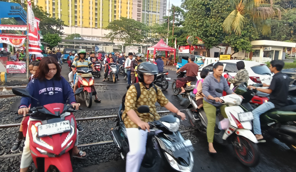 Jumlah Angka Kecelakaan Kereta Api Meningkat Sejumlah pengendara sepeda motor menyeberangi jalur perlintasan kereta api di kawasan Menteng, Jakarta, Kamis (14/8/2025). (Beritanasional.com/Oke Atmaja)