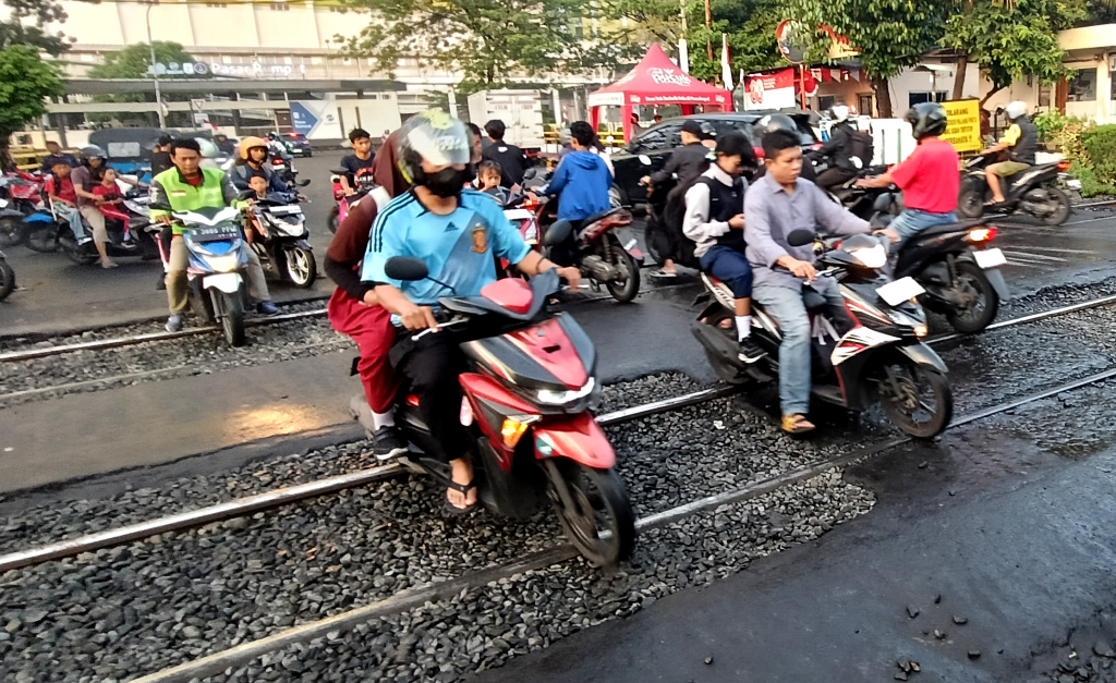 Jumlah Angka Kecelakaan Kereta Api Meningkat Sejumlah pengendara sepeda motor menyeberangi jalur perlintasan kereta api di kawasan Menteng, Jakarta, Kamis (14/8/2025). (Beritanasional.com/Oke Atmaja)