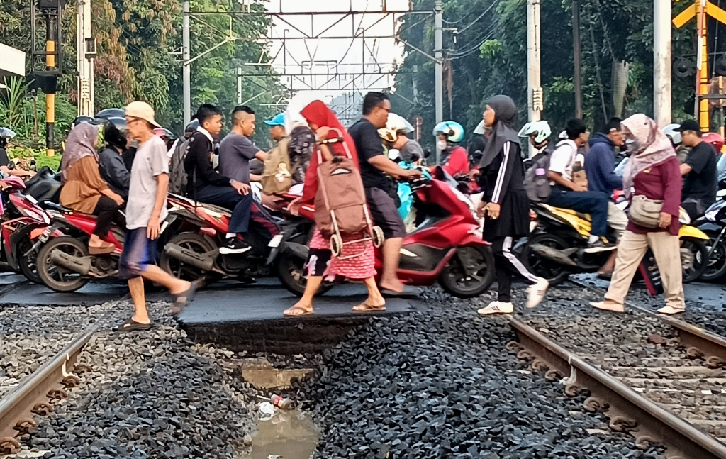 Jumlah Angka Kecelakaan Kereta Api Meningkat Sejumlah pengendara sepeda motor menyeberangi jalur perlintasan kereta api di kawasan Menteng, Jakarta, Kamis (14/8/2025). (Beritanasional.com/Oke Atmaja)