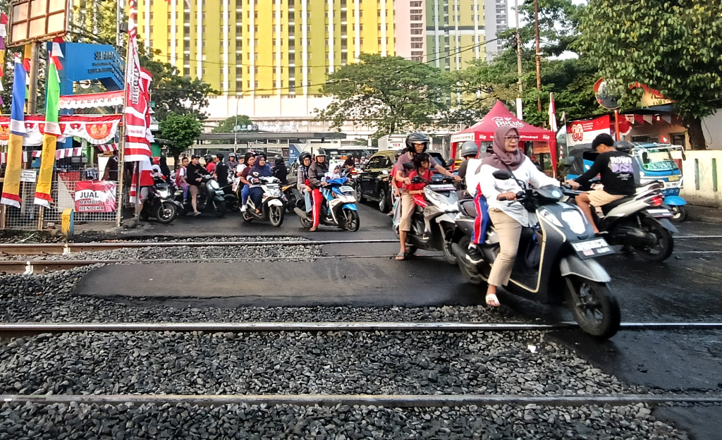 Jumlah Angka Kecelakaan Kereta Api Meningkat Sejumlah pengendara sepeda motor menyeberangi jalur perlintasan kereta api di kawasan Menteng, Jakarta, Kamis (14/8/2025). (Beritanasional.com/Oke Atmaja)