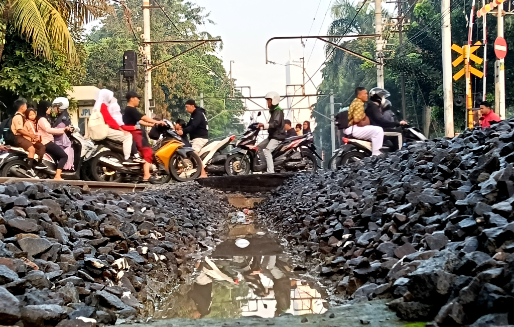 Jumlah Angka Kecelakaan Kereta Api Meningkat Sejumlah pengendara sepeda motor menyeberangi jalur perlintasan kereta api di kawasan Menteng, Jakarta, Kamis (14/8/2025). (Beritanasional.com/Oke Atmaja)