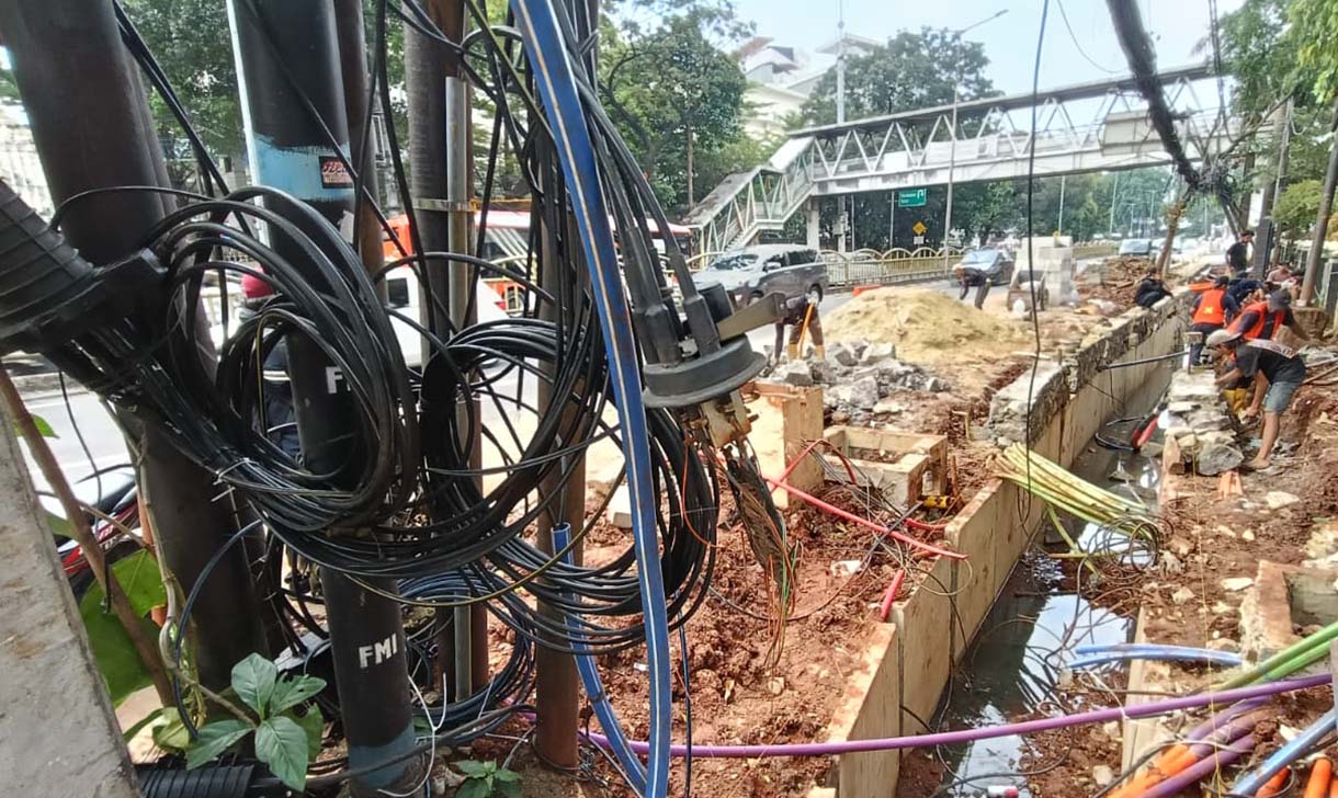 Kabel Semrawut di Tebet Warga melintas di samping kabel utilitas yang semrawut dikawasan Tebet, Jakarta, Jumat (31/10/2025).   (Beritanasional.com/Oke Atmaja)