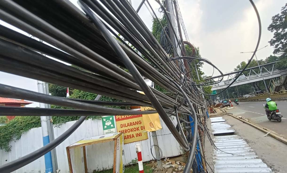Kabel Semrawut di Tebet Warga melintas di samping kabel utilitas yang semrawut dikawasan Tebet, Jakarta, Jumat (31/10/2025).   (Beritanasional.com/Oke Atmaja)