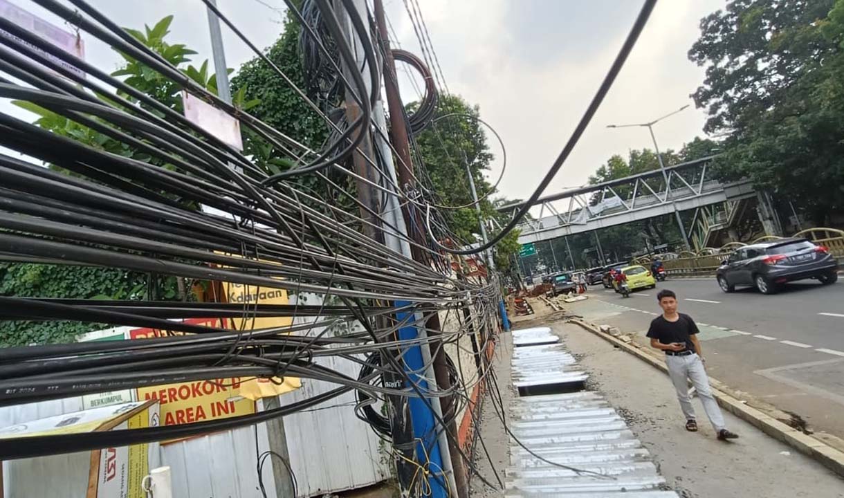 Kabel Semrawut di Tebet Warga melintas di samping kabel utilitas yang semrawut dikawasan Tebet, Jakarta, Jumat (31/10/2025).   (Beritanasional.com/Oke Atmaja)