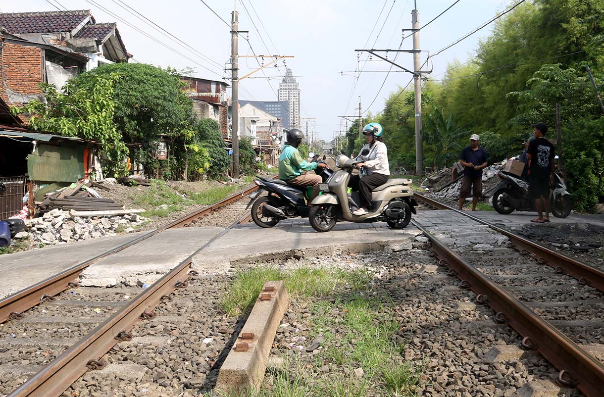 Warga dan pengendara motor melintasi perlintasan sebidang di kawasan Tebet Timur, Jakarta, Selasa (19/5/2026).  (Beritanasional.com/Oke Atmaja)
