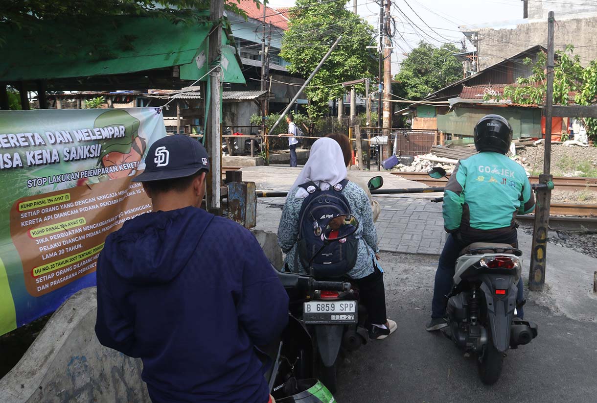 Warga dan pengendara motor melintasi perlintasan sebidang di kawasan Tebet Timur, Jakarta, Selasa (19/5/2026).  (Beritanasional.com/Oke Atmaja)