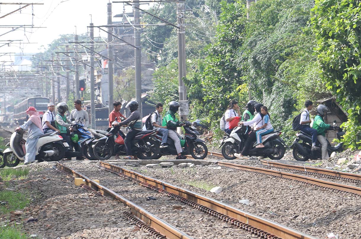 Warga dan pengendara motor melintasi perlintasan sebidang di kawasan Tebet Timur, Jakarta, Selasa (19/5/2026).  (Beritanasional.com/Oke Atmaja)