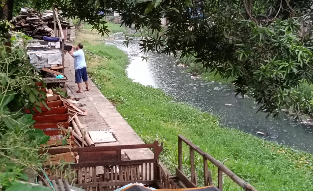 Seorang warga beraktivitas di bantaran Kali Ciliwung kawasan Matraman, Jakarta Timur, Selasa (14/4/2026). (Beritanasional.com/Oke Atmaja).