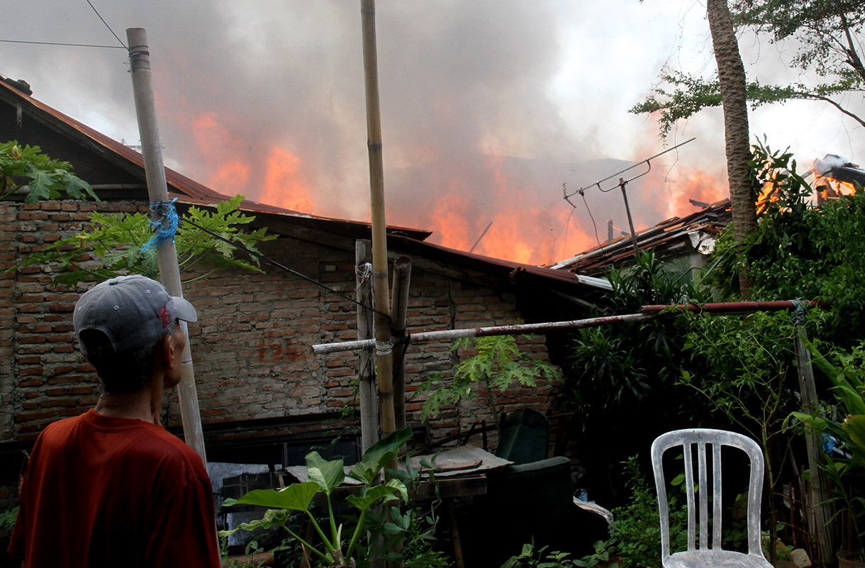 Warga berusaha memadamkan api yang membakar permukiman padat di Kawasan Menteng, Jakarta Pusat, Jumat (20/12/2024).(BeritaNasional.com/Oke Atmaja)