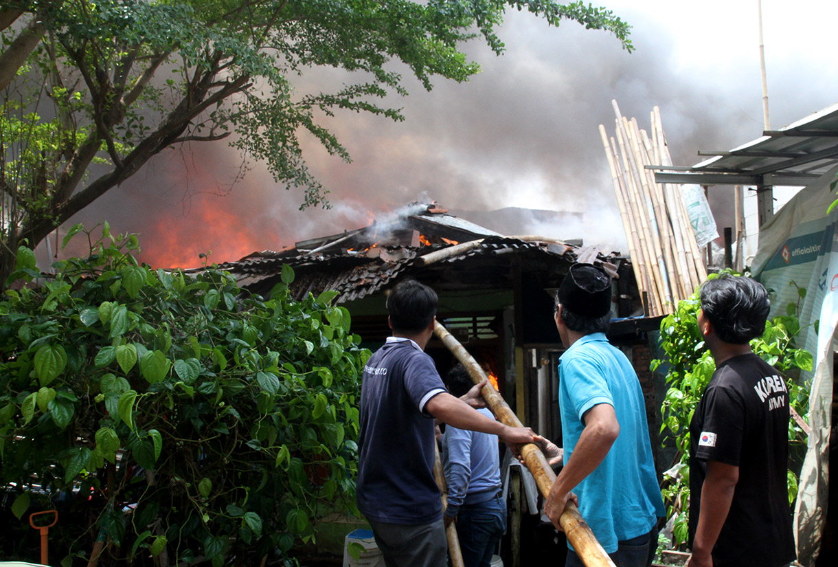 Warga berusaha memadamkan api yang membakar permukiman padat di Kawasan Menteng, Jakarta Pusat, Jumat (20/12/2024).(BeritaNasional.com/Oke Atmaja)