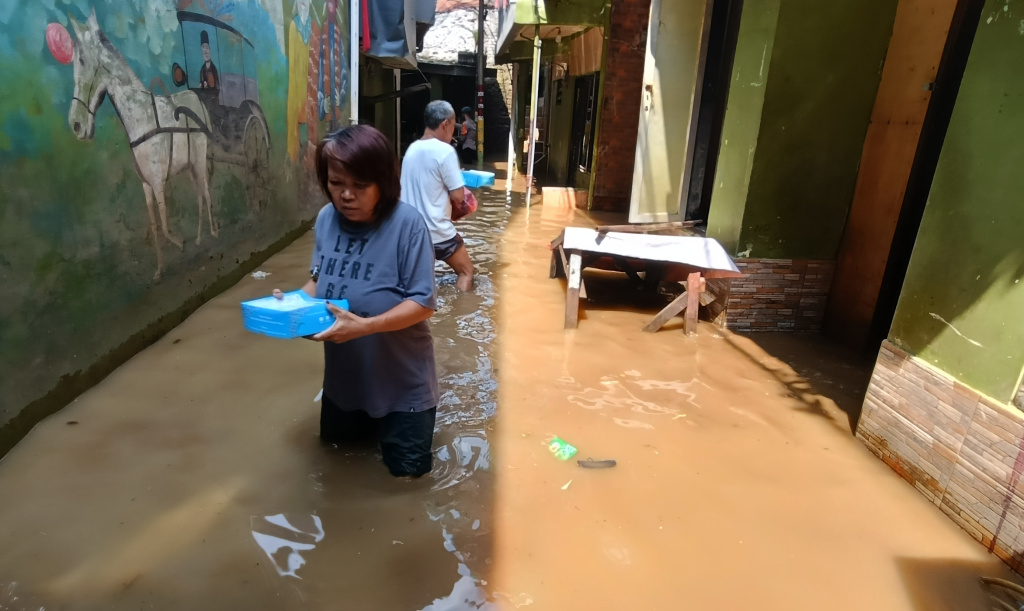 Kebon Pala Jaktim Masih Terendam Banjir Warga melintasi banjir di Kebon Pala, Jatinegara, Jakarta Timur, Senin (7/7/2025). (Beritanasional.com/Oke Atmaja)