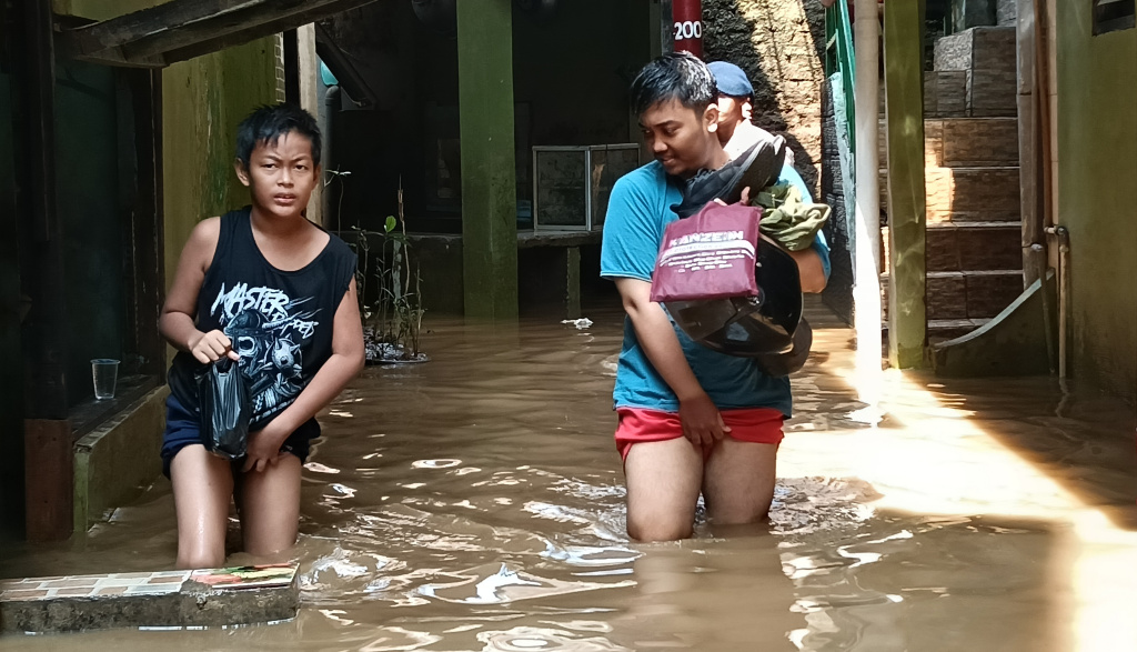 Warga melintasi banjir di Kebon Pala, Jatinegara, Jakarta Timur, Senin (7/7/2025).  (Beritanasional.com/Oke Atmaja)