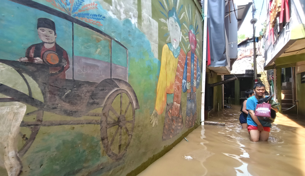 Warga melintasi banjir di Kebon Pala, Jatinegara, Jakarta Timur, Senin (7/7/2025).  (Beritanasional.com/Oke Atmaja)