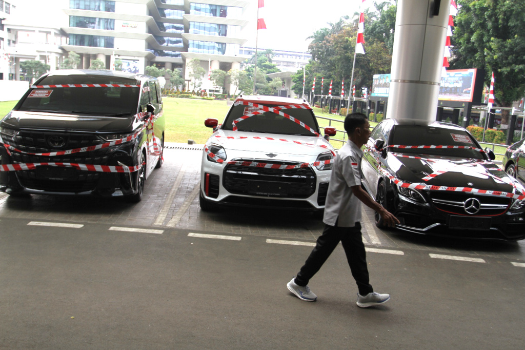 Kejagung Sita Mobil Mewah Diduga Milik Riza Chalid Warga melintas di depan sejumlah mobil sitaan penyidik Jaksa Agung Muda Bidang Tindak Pidana Khusus (Jampidsus) di Kejaksaan Agung, Jakarta, Selasa (5/8/2025). (Beritanasional.com/Oke Atmaja)