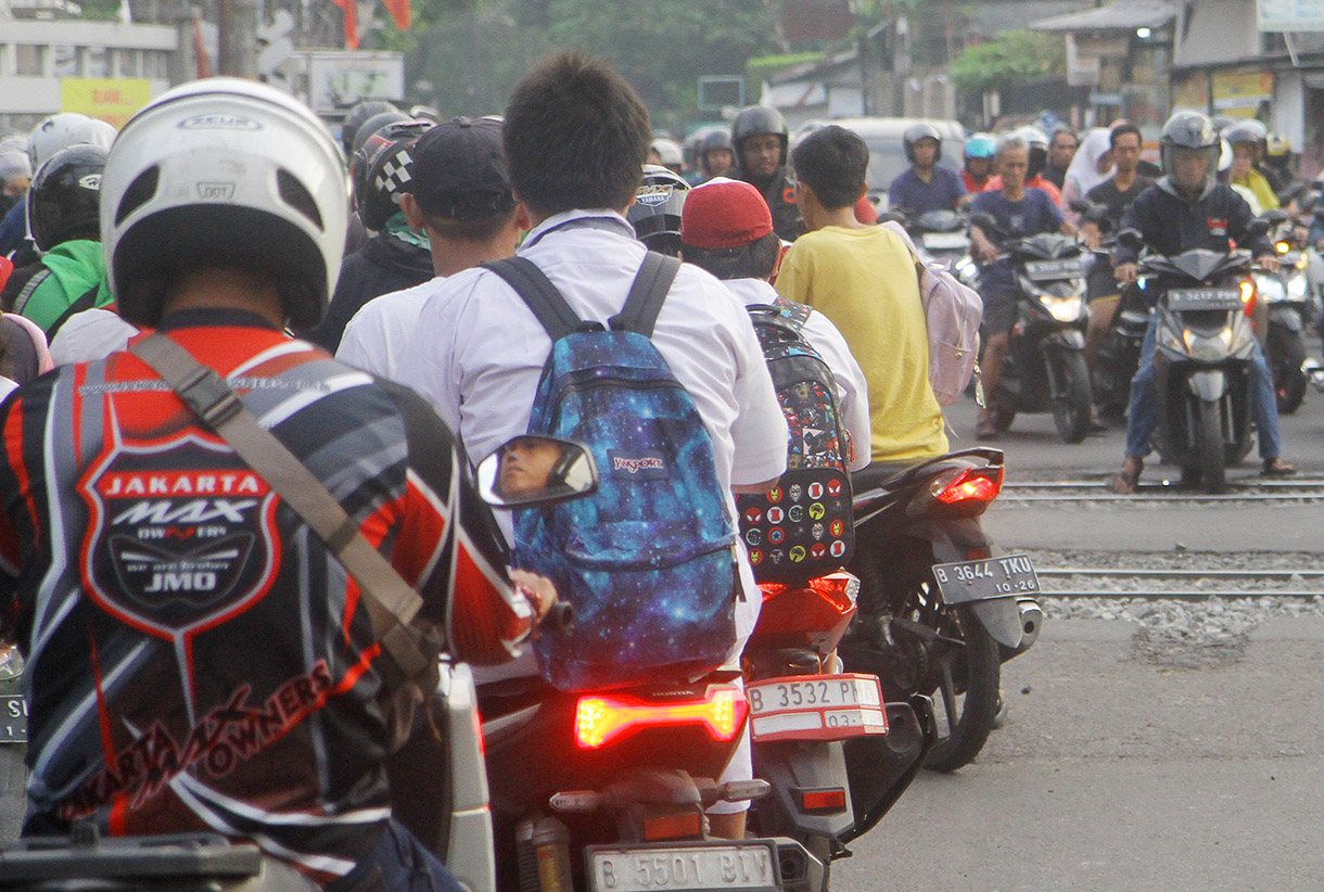 Pengendar motor melintasi pintu kereta di Jalan Menteng Jaya, Jakarta, Rabu (24/7/2024).(BeritaNasional.com/Oke Atmaja)