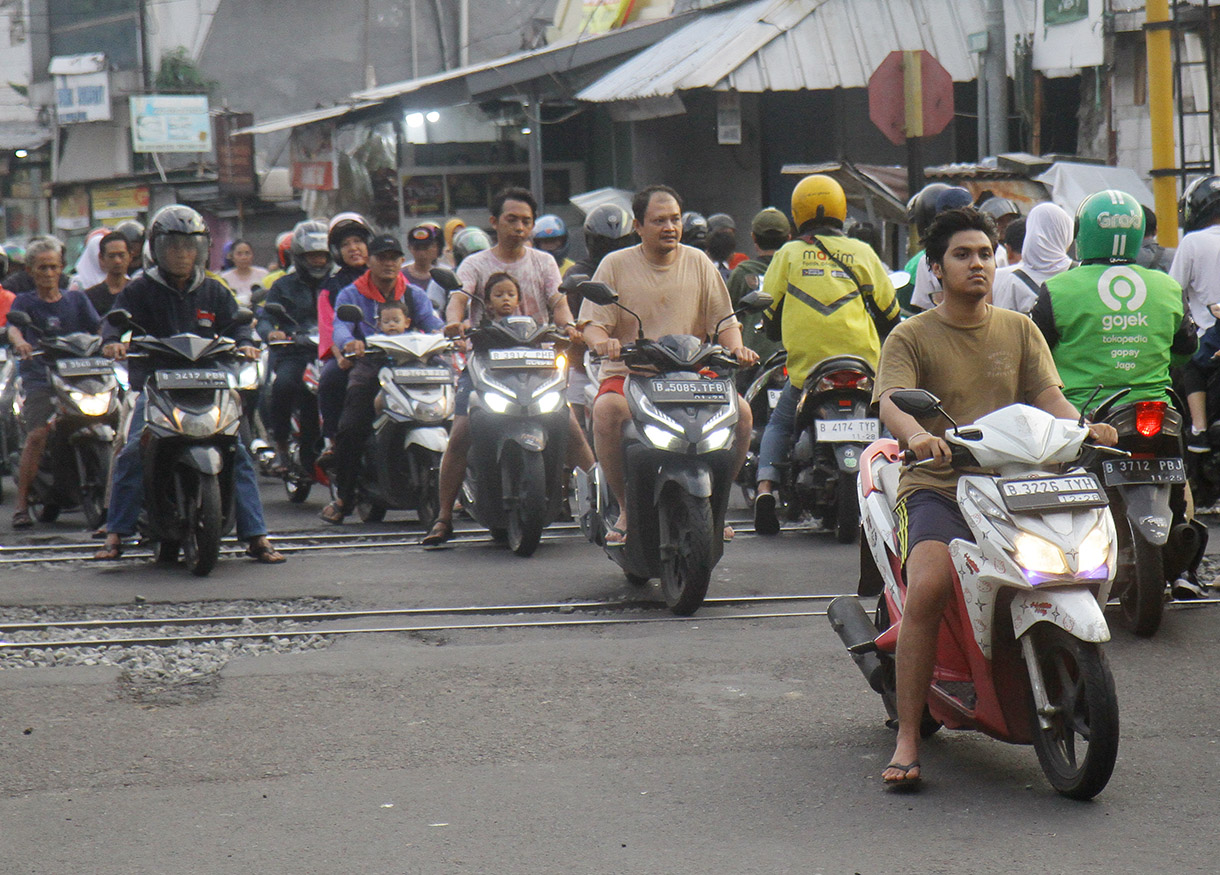 Pengendar motor melintasi pintu kereta di Jalan Menteng Jaya, Jakarta, Rabu (24/7/2024).(BeritaNasional.com/Oke Atmaja)