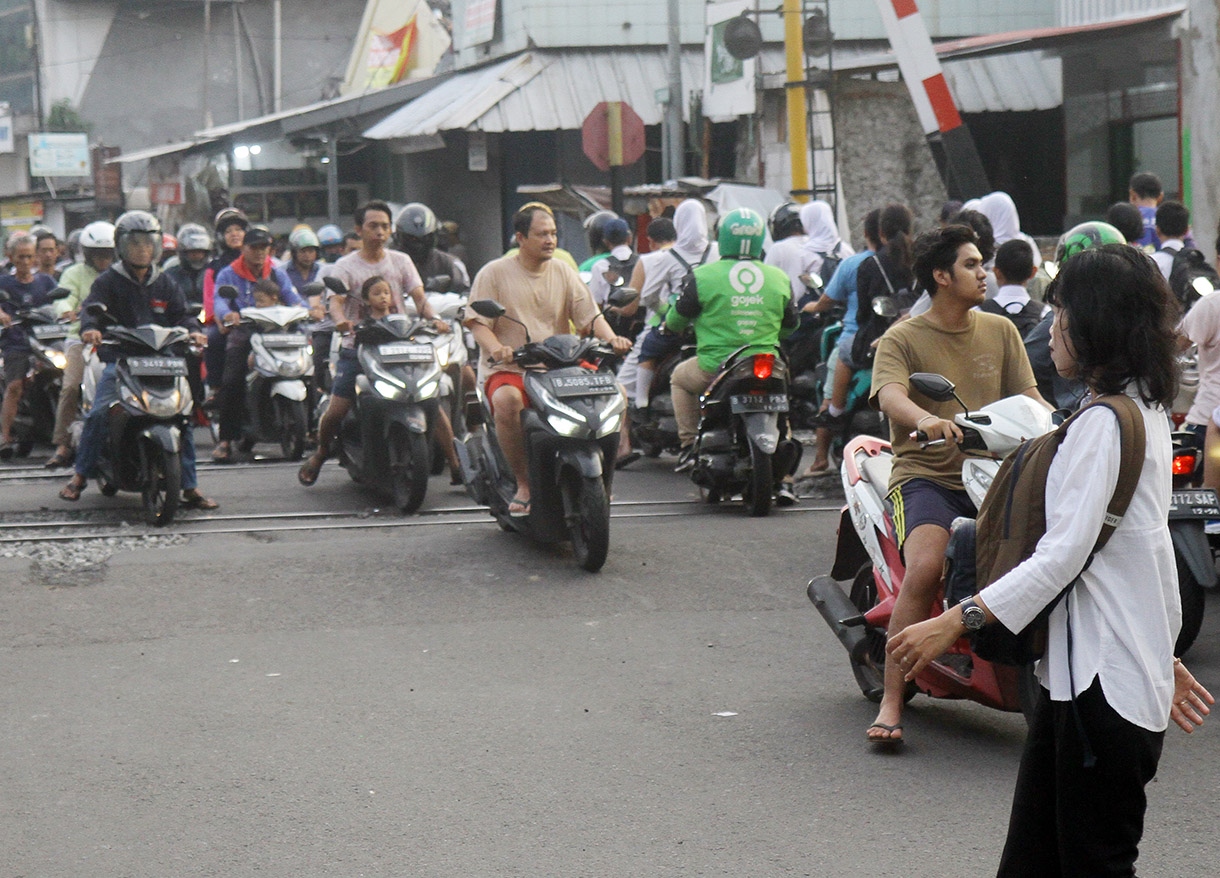 Pengendar motor melintasi pintu kereta di Jalan Menteng Jaya, Jakarta, Rabu (24/7/2024).(BeritaNasional.com/Oke Atmaja)